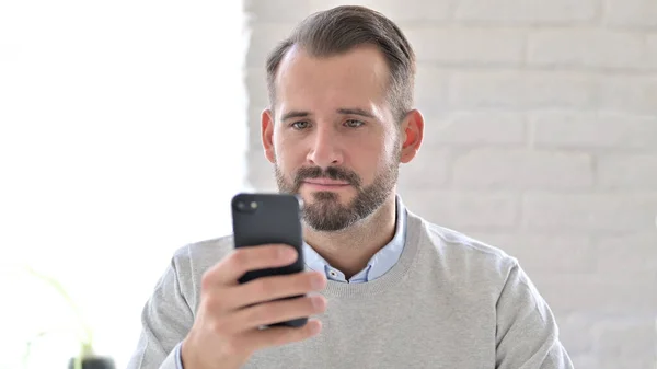 Портрет привлекательного молодого человека с помощью смартфона — стоковое фото