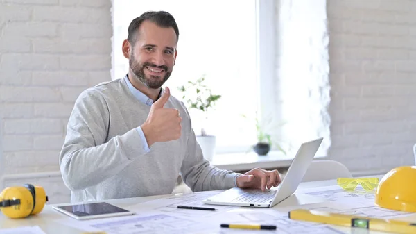 Positiv ung arkitekt med bärbar dator gör tummen upp i Office — Stockfoto