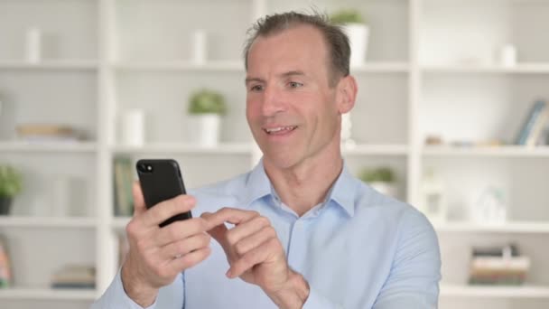 Portré a középkorú üzletemberről, aki a sikert ünnepli okostelefonon — Stock videók