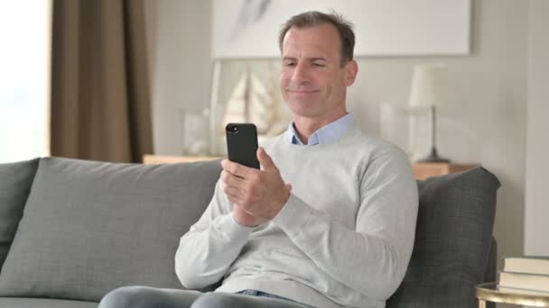 Attraktiv medelålders affärsman med Smartphone på soffan — Stockvideo