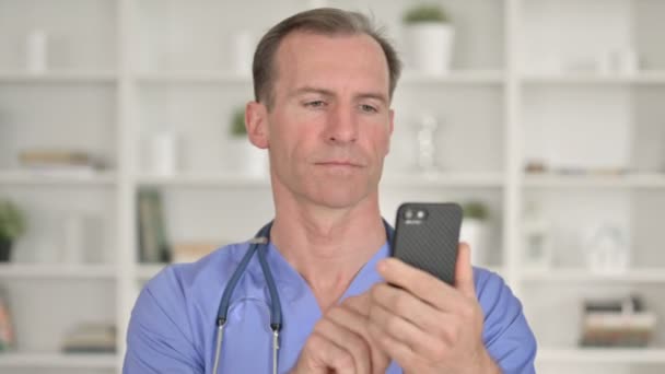Портрет жизнерадостного врача средних лет, говорящего по смартфону — стоковое видео