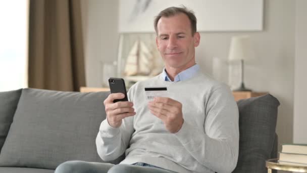 Emocionado hombre de mediana edad haciendo el pago exitoso en el teléfono inteligente — Vídeo de stock