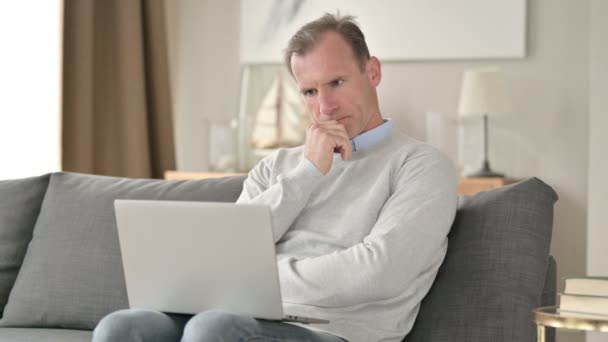 Empresario de mediana edad Pensando y trabajando en el ordenador portátil en el sofá — Vídeos de Stock