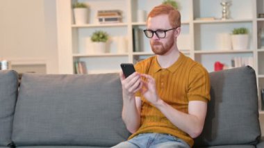 Neşeli Kızıl Adam evde akıllı telefon kullanıyor. 