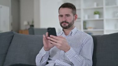 Evde akıllı telefon kullanan çekici genç adam. 