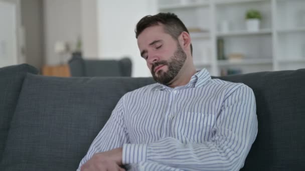 Уставший молодой человек дремлет на диване — стоковое видео