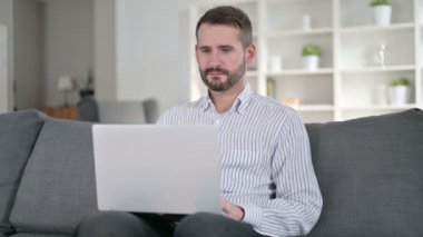 Neşeli Genç Adam evdeki laptopta görüntülü sohbet yapıyor. 