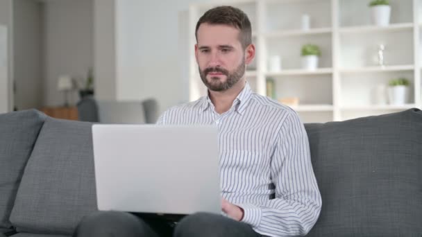 Jovem alegre fazendo bate-papo de vídeo no laptop em casa — Vídeo de Stock