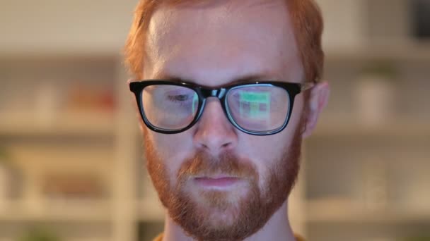 Primer plano de la cara del hombre pelirrojo utilizando dispositivo reflejado en gafas — Vídeos de Stock