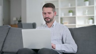 Bilgisayarlı yorgun genç adam evde baş ağrısı çekiyor. 