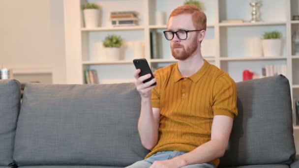Hombre pelirrojo feliz hablando en Smartphone en casa — Vídeo de stock