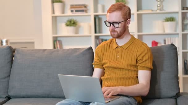 Redhead Man firar framgång på laptop hemma — Stockvideo