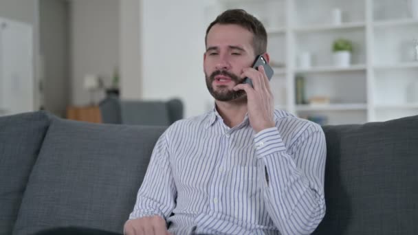Veselý mladý muž mluví na chytrém telefonu doma — Stock video