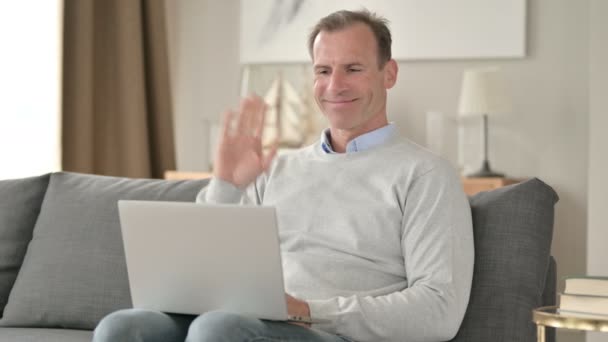 Medelålders affärsman gör videochatt på laptop på soffan — Stockvideo