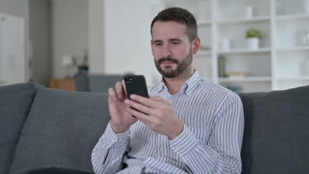 Törekvő fiatalember ünnepli a sikert az okostelefonon — Stock videók