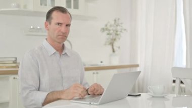 Dizüstü bilgisayarı olan orta yaşlı bir adam Parmakla İşaret Göstermiyor