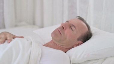 Orta yaşlı hasta adam yatakta uyuyor ve öksürüyor.