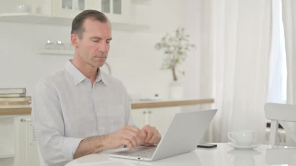 Alegre hombre de mediana edad con el ordenador portátil sonriendo a la cámara — Vídeo de stock