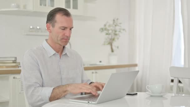 Uomo di mezza età che celebra il successo sul computer portatile a casa — Video Stock