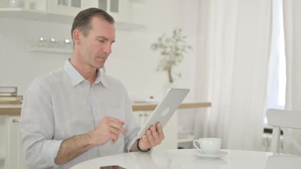 Wesoły mężczyzna w średnim wieku za pomocą tabletu w domu — Wideo stockowe