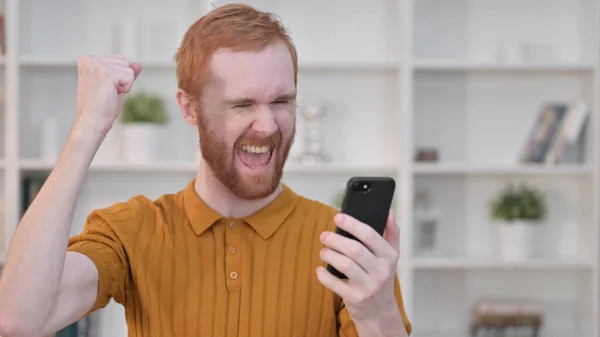 红头发男人用智能手机庆祝成功的肖像 — 图库照片