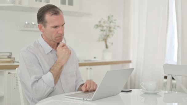 Homem de meia-idade Pensando e trabalhando no laptop em casa — Vídeo de Stock