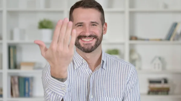 Portret van een jonge man wijzend vinger en uitnodigend — Stockfoto