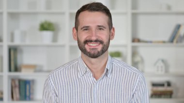 Kameraya bakan gülümseyen genç adamın portresi. 