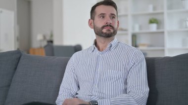 Düşünen genç adam evde oturuyor. 