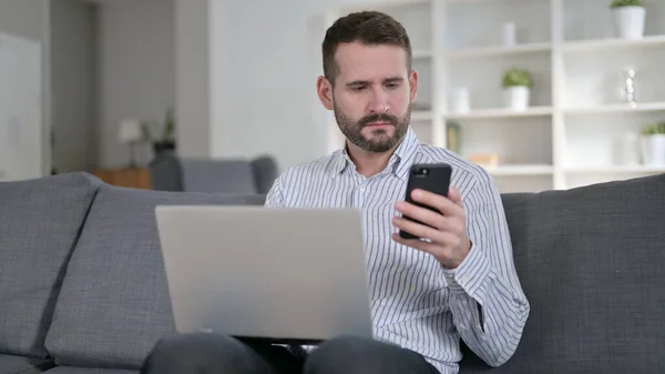 Focused Man working on Smartphone and Laptop at Home — Stock Photo, Image