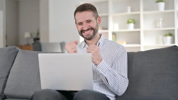 Uomo ambizioso che celebra il successo sul computer portatile a casa — Foto Stock