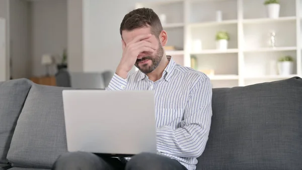 Frustrado jovem homem com dor de cabeça ao usar laptop — Fotografia de Stock