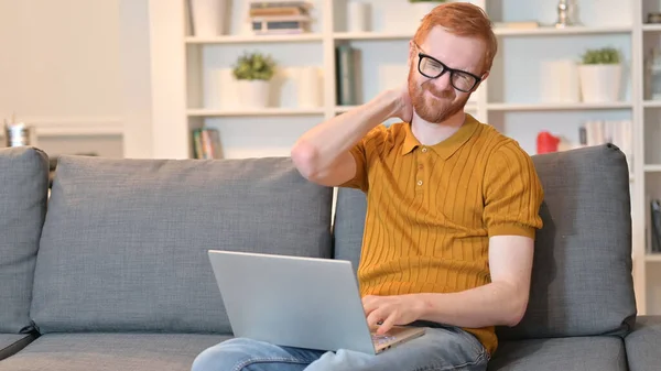 Redhead Man with Neck Pain working on Laptop at Home