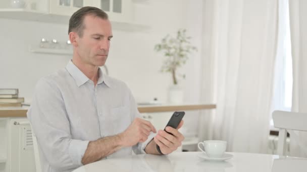 Alegre hombre de mediana edad hablando en Smartphone en casa — Vídeo de stock