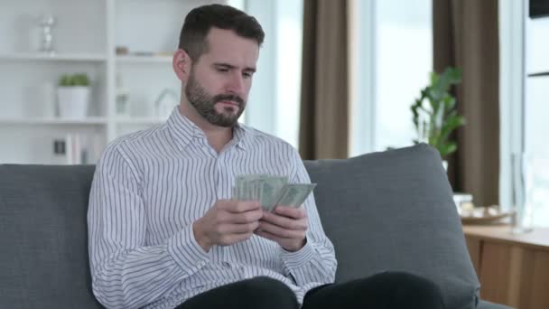 Giovane imprenditore concentrato che conta dollari a casa — Video Stock