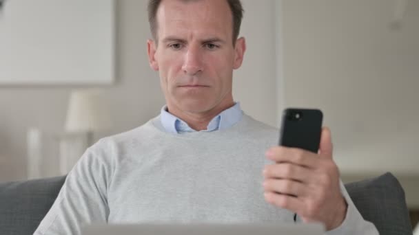 Porträtt av medelålders affärsman med hjälp av smartphone och bärbar dator — Stockvideo