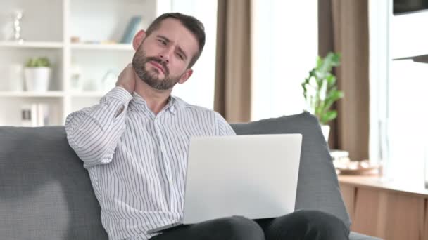 Уставший молодой бизнесмен с ноутбуком, имеющий боль в шее дома — стоковое видео
