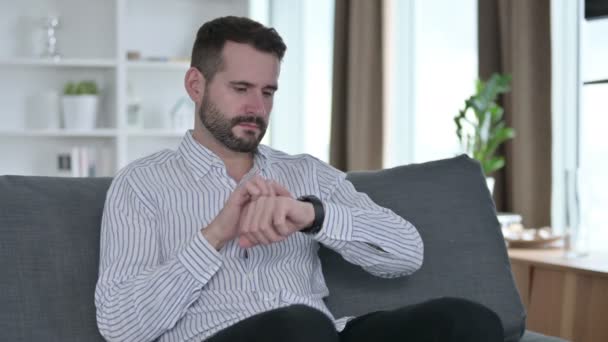 Uvolněný mladý podnikatel používající Smart Watch doma — Stock video