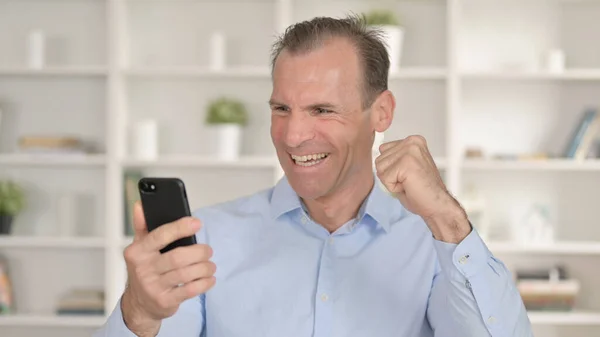 Portret van de middelbare leeftijd Zakenman viert succes op Smartphone — Stockfoto
