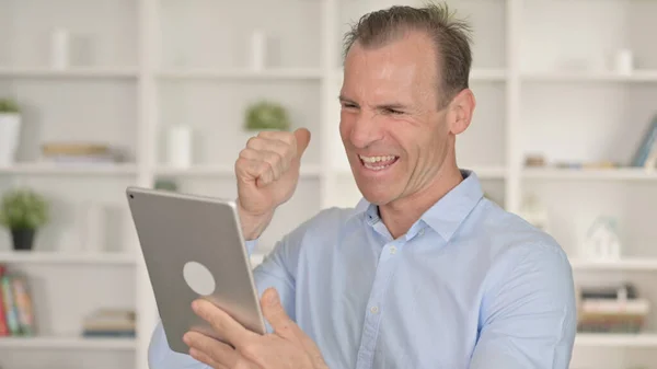 Porträt eines Geschäftsmannes mittleren Alters, der Erfolg auf dem Tablet feiert — Stockfoto