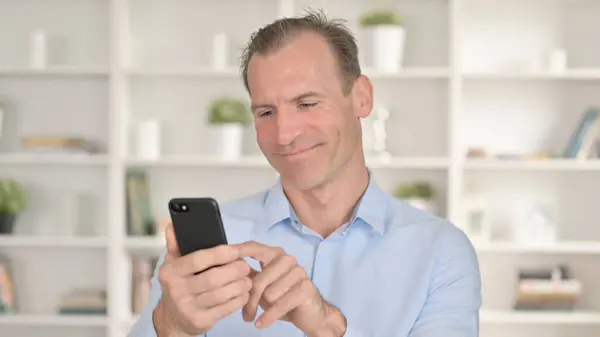 Porträt eines fokussierten Geschäftsmannes mittleren Alters mit Smartphone — Stockfoto