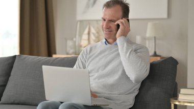 Neşeli Orta Çağ İşadamı Kanepede Smartphone 'da konuşuyor