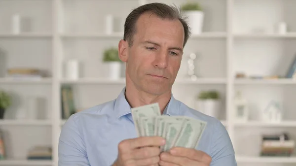 Portret van een zakenman van middelbare leeftijd die dollars telt — Stockfoto