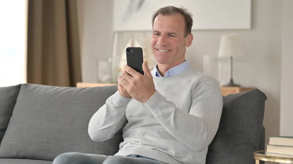 Middle Aged Businessman Celebrating Success on Smartphone on Sofa — Stock Photo, Image