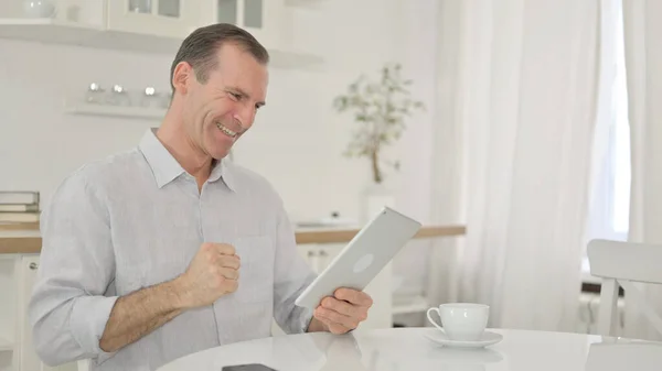 Homme du Moyen Âge excité ayant du succès sur tablette à la maison — Photo