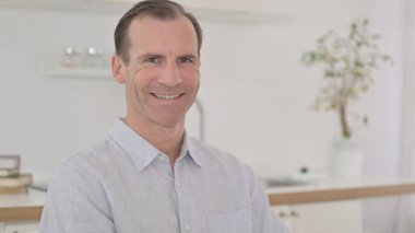 Kameraya gülümseyen neşeli orta yaşlı adamın portresi.