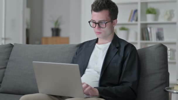 Atractivo joven diseñador masculino con el ordenador portátil sonriendo a la cámara — Vídeo de stock