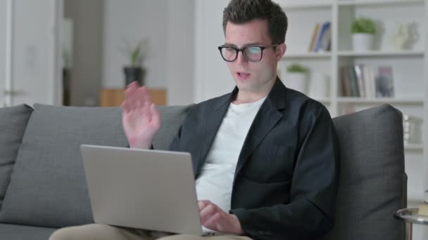 Jovem Designer do sexo masculino fazendo chamada de vídeo no laptop em casa — Vídeo de Stock