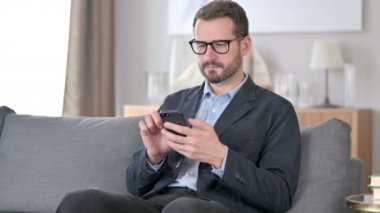 Evde akıllı telefon kullanan çekici genç iş adamı.
