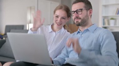 Neşeli Genç Çift evdeki laptopta video görüşmesi yapıyor.